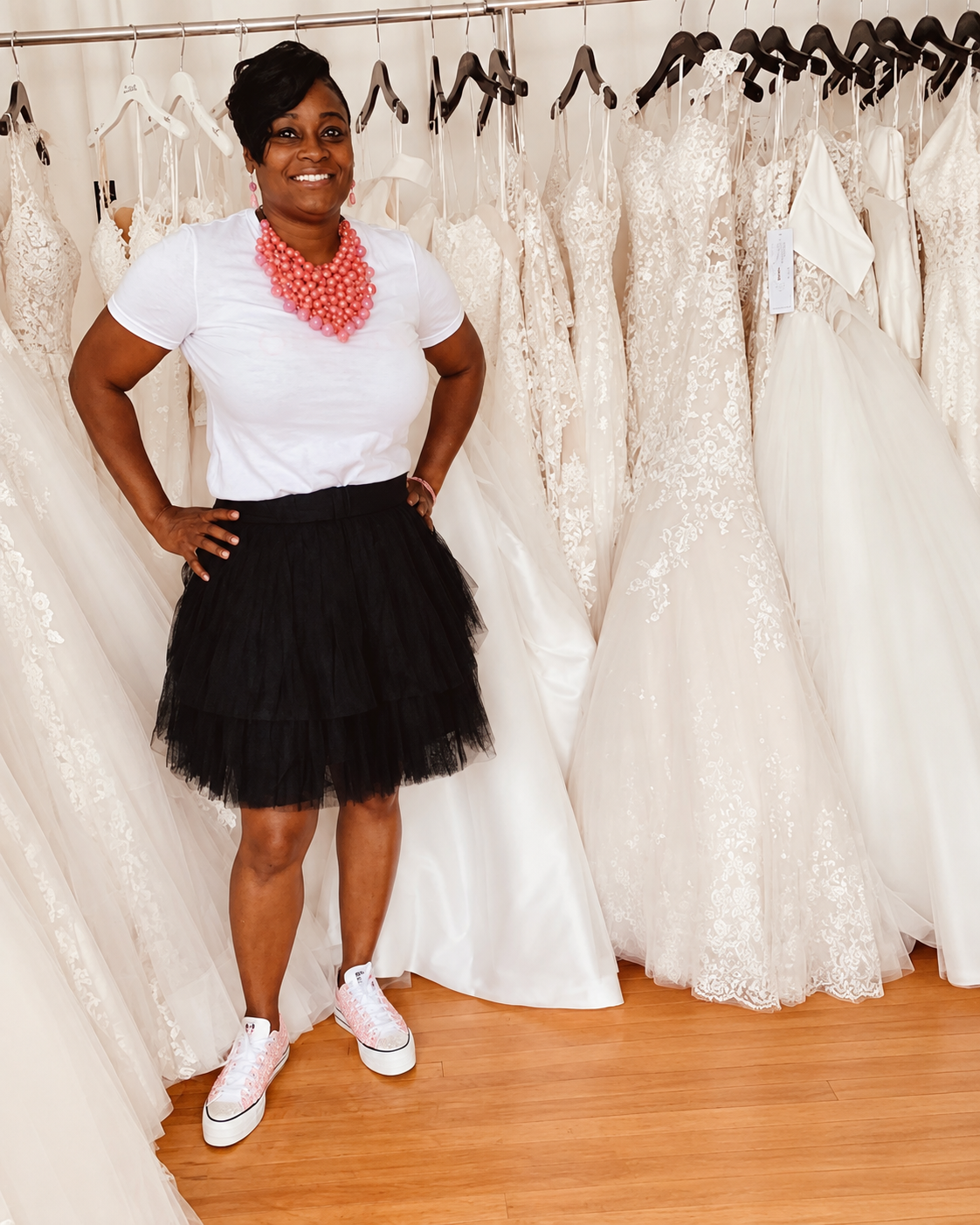 Char, owner of Char Bridals, standing with wedding gowns inside her boutique